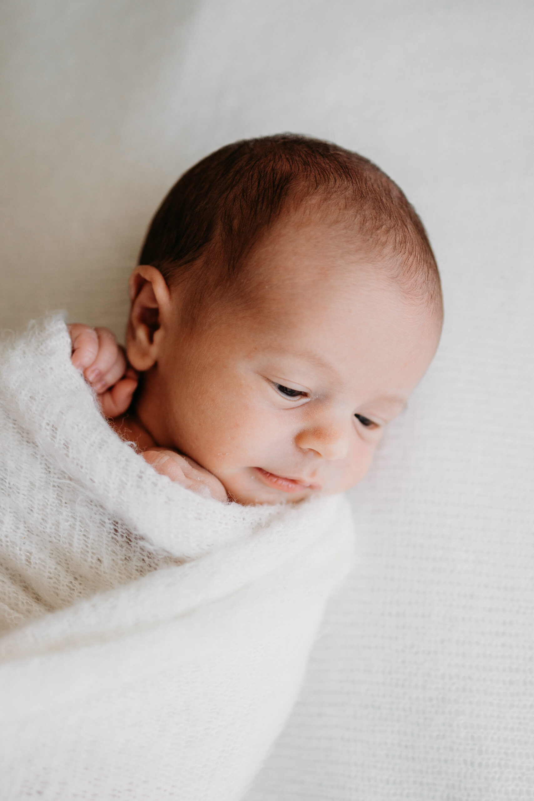 Neugeborenes auf einer weissendecke beim Natürlichem Newborn Fotoshooting im Zürich Oberland